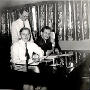 Steve Cole (standing), Al LaGuire, and John Porterfield in the WMTE studio during the 5th Anniversary of the station.